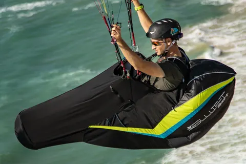 APCO Swift Sport Liegegurtzeug – Pilot mit Helm im Flug, Seitenansicht über dem Wasser